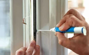 a-person-applying-caulk-to-seal-a-window-frame-ensuring-no-gaps-where-spiders-can-enter-the-house